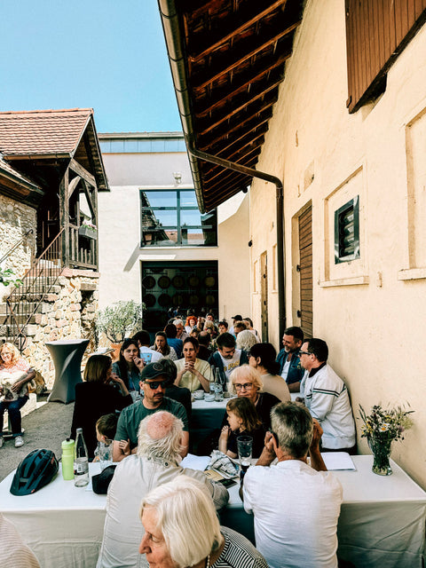Gäste an langen Tischen im Innenhof des Weinguts Zelt beim Hoffest